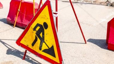 Şehir caddesinde trafik tabelasında çalışıyor. Yol tabelasının altında