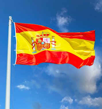 Mavi gökyüzüne karşı rüzgarda dalgalanan İspanyol bayrağı