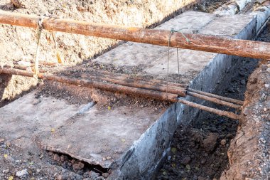 Isıtma borularının değiştirilmesi ve ısıtma sisteminin modernizasyonu. İnşaat, kazılmış hendek derinliğindeki büyük demir borular üzerinde çalışıyor.