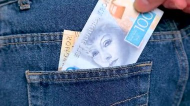 Swedish krona banknotes being taken out of a back jeans pocket