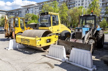 Samara, Russia - May 13, 2017: Road roller and wheeled tractor on the construction of new road. Road construction machinery clipart