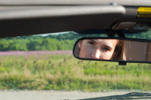 Brunette vrouw kijken op achteruitkijkspiegel — Stockfoto