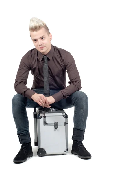 Красивый мужчина, сидящий на чемодане — стоковое фото