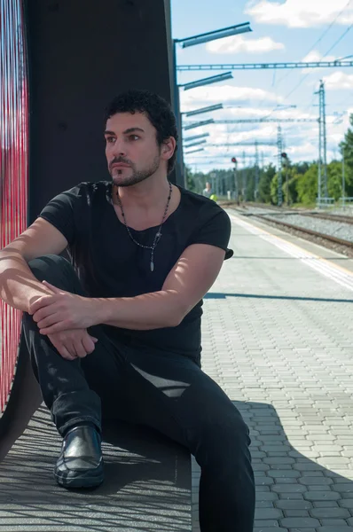 Schöner Mann sitzt auf Bahnsteig — Stockfoto