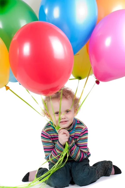 Liten flicka med mångfärgade air ballonger sitter — Stockfoto