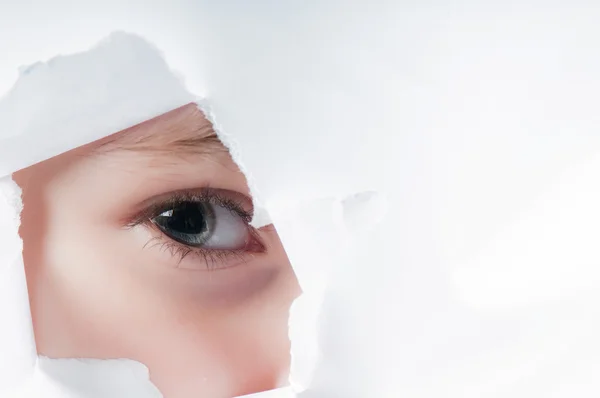 Child eye looking through a hole in paper — Stock Photo, Image