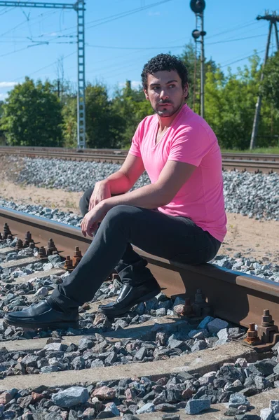 Young man sitting on the rail track — Stock Photo, Image