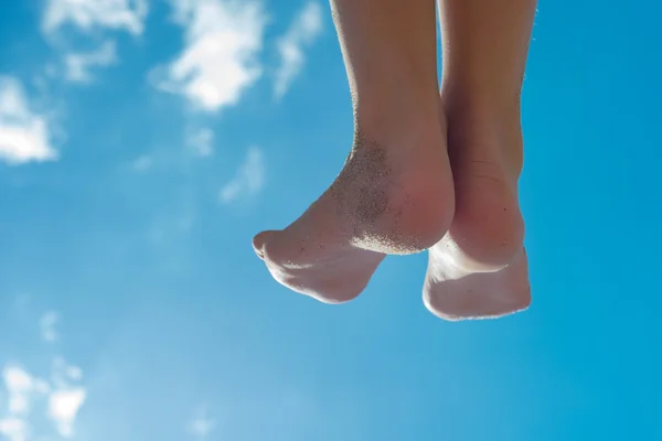 Crianças pés contra o céu azul — Fotografia de Stock