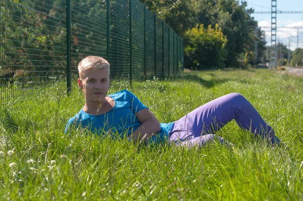 Jonge man liggend op het groene gras — Stockfoto