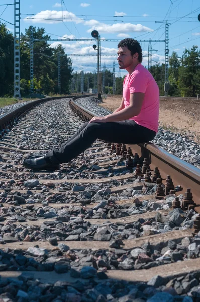 Único homem de t-shirt rosa sentado em trilhos de trem — Fotografia de Stock