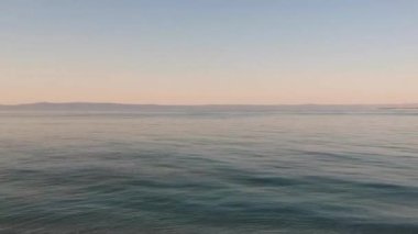 Güzel bir deniz görüntüsü. Mavi deniz suyunun üzerinde sakin bir gündoğumuyla sahilin havadan çekilmiş görüntüsü. Adriyatik Denizi 'nin güzel kıyıları. Bulutlu körfez manzarası. Gün doğumu.
