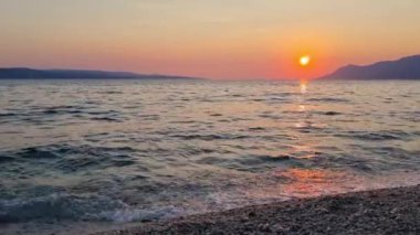 Büyük deniz dalgaları kıyı şeridinde dalgalanırken güzel görüntüler. Adriyatik Denizi üzerinde güzel kırmızı gün batımı. Makarska Riviera-Biokovo, Dalmaçya, Hırvatistan, Avrupa.