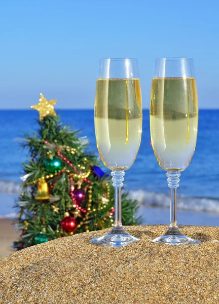 Glasses of champagne and Christmas tree on the beach — Stock Photo, Image