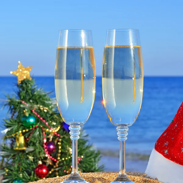 Glasses of champagne and Christmas tree on the beach — Stock Photo, Image