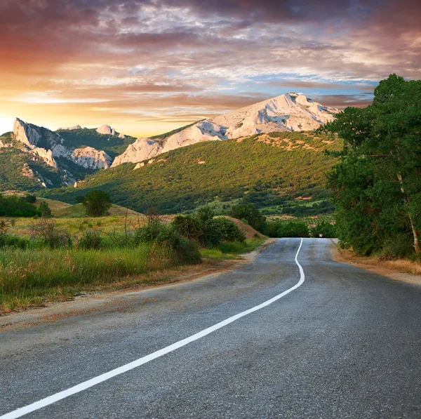 Vieja carretera contra montañas al atardecer —  Fotos de Stock