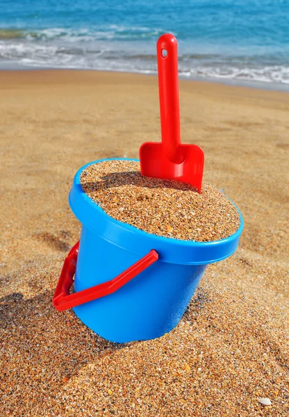 婴儿桶与沙子和一把铲子在海滩上 — 图库照片
