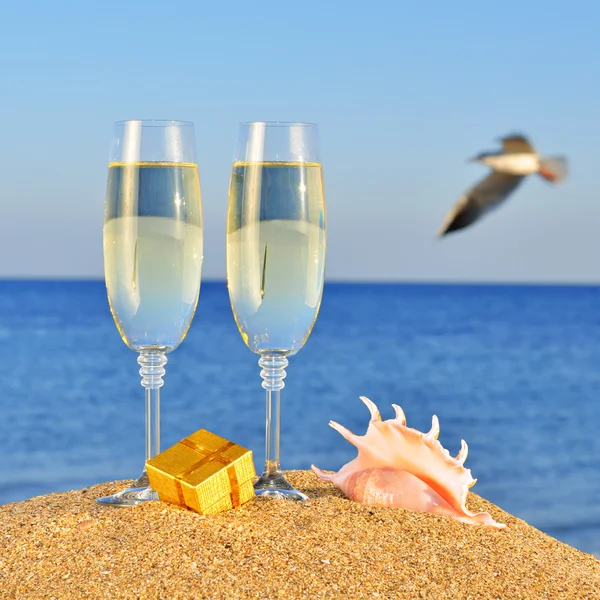 Glasses of champagne, box with a gift and seashel — Stock Photo, Image