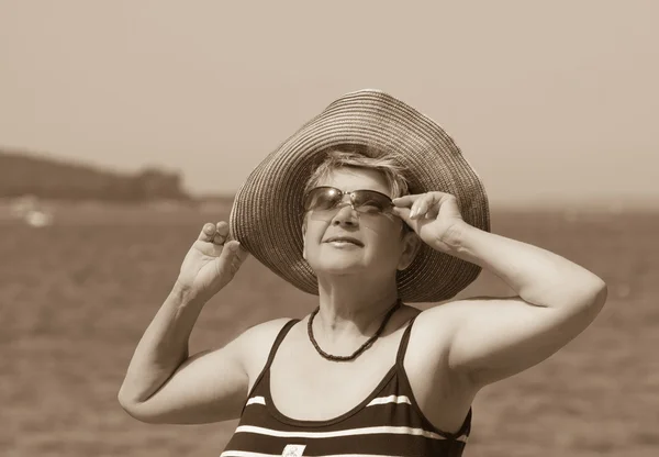 Una donna con un cappello sullo sfondo del mare — Foto Stock