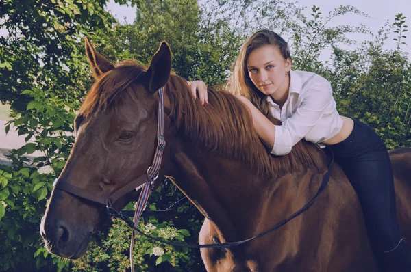 Fästmö i en bröllopsklänning grensle på en häst — Stockfoto