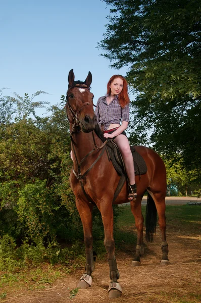 Mulher com cabelo vermelho sentado em um cavalo — Fotografia de Stock