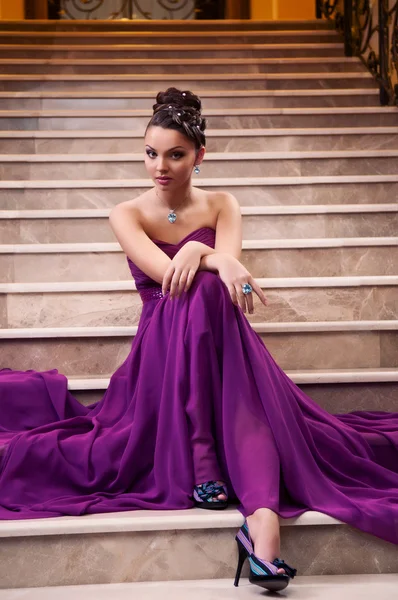 Mulher em um vestido longo está sentado nas escadas — Fotografia de Stock