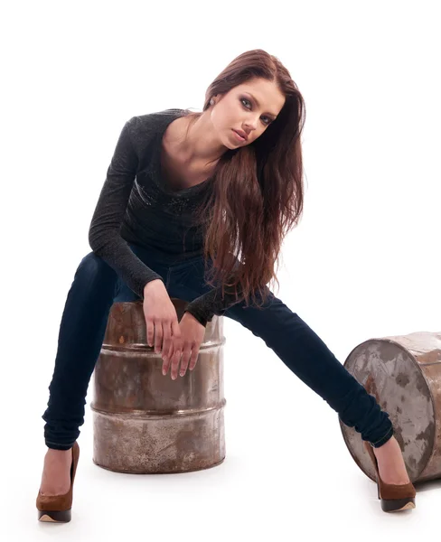 Girl in jeans sitting on an iron barrel — Stock Photo, Image