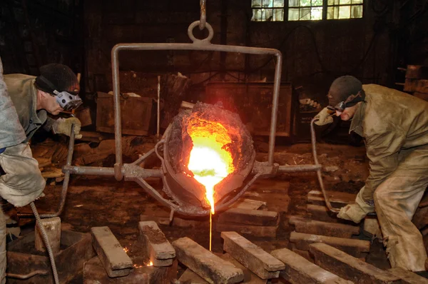 Литейное производство - расплавленный металл, выливающийся из ковша в форму — стоковое фото