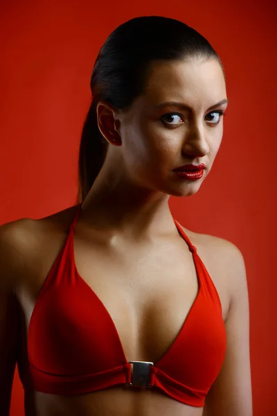 Mooie brunette in lingerie op rode achtergrond — Stockfoto