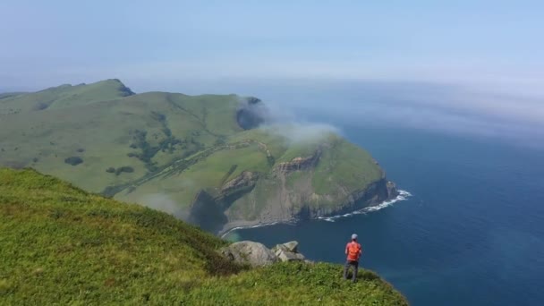 積丹島の端に立って太平洋を見ている旅行者の上にドローンショット 少ないカーリルチェーン ロシア — ストック動画