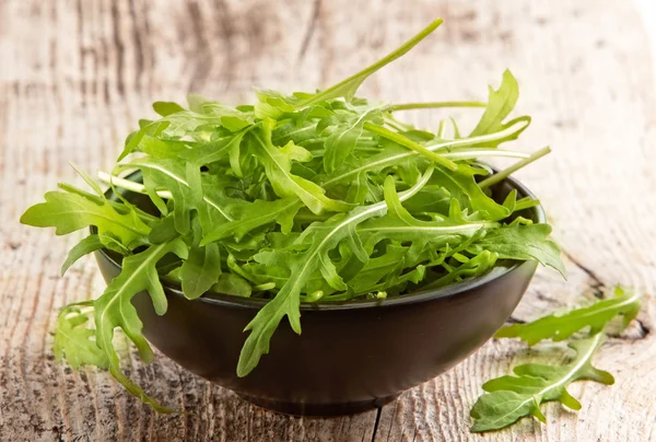 Rucola em tigela preta — Fotografia de Stock