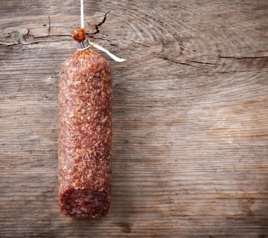 Hanging salami sausage on wooden background clipart
