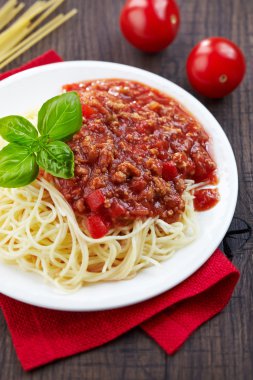 Beyaz tabak spagetti bolognese ve yeşil fesleğen yaprağı
