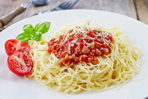 Beyaz tabak spagetti bolognese ve yeşil fesleğen yaprağı — Stok fotoğraf