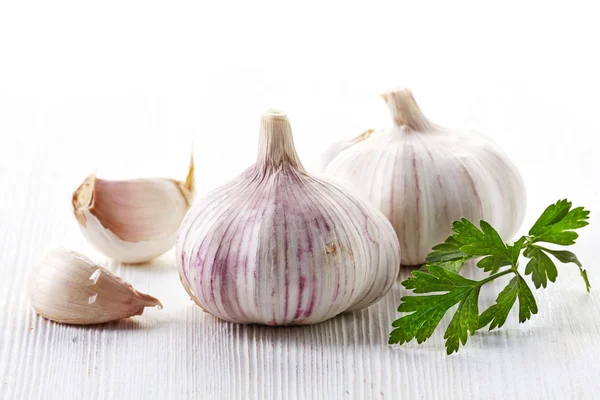 Garlic and parsley on a white wooden table — Stock Photo, Image