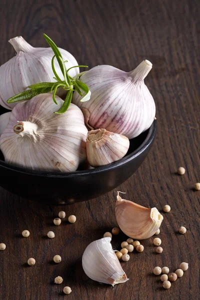 Alho e pimenta branca na mesa de madeira marrom — Fotografia de Stock