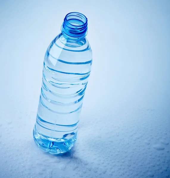 Plastic fles water op natte blauwe achtergrond — Stockfoto