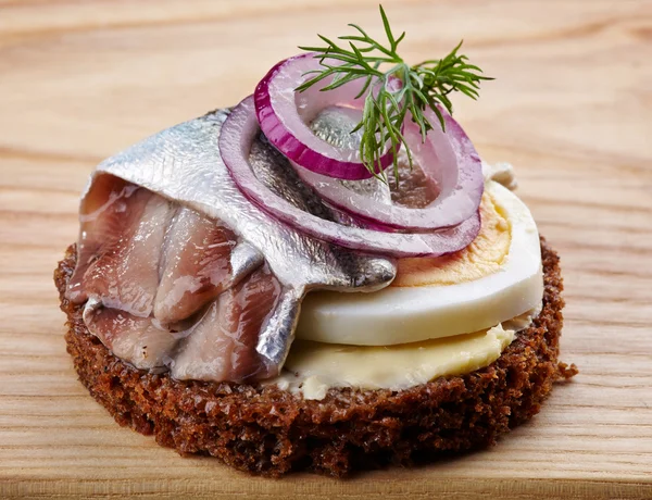 Brown bread canape with anchovies decorated with red onion and d — Stock Photo, Image