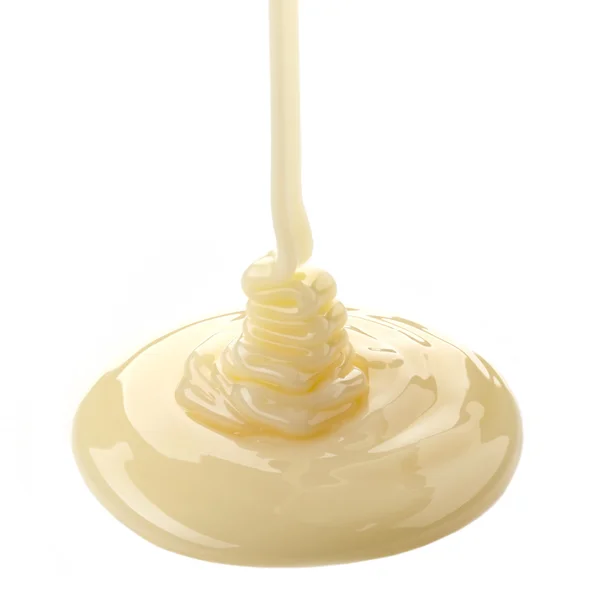 Verter leite condensado sobre um fundo branco — Fotografia de Stock
