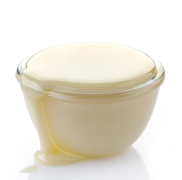 Hälla kondenserad mjölk med socker i en skål — Stockfoto