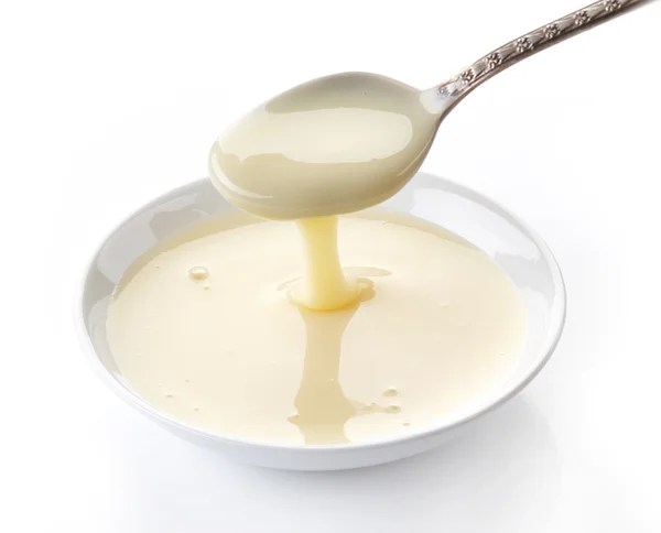 Gieten van gecondenseerde melk met suiker in een kom — Stockfoto