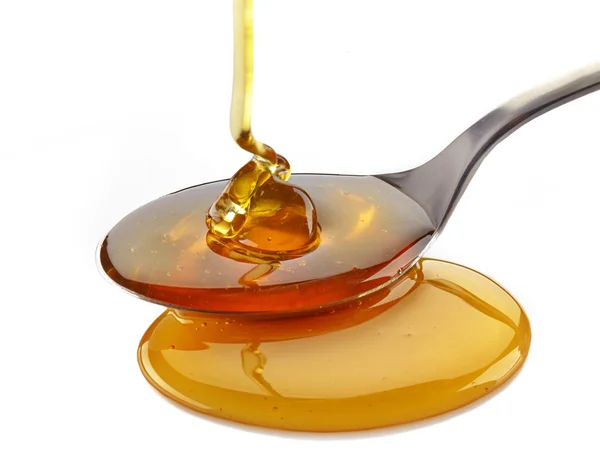 Honning hælde i ske - Stock-foto