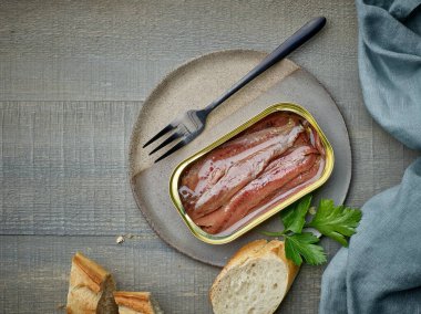 Konserve ançüez fileto ve ekmek dilimleri ahşap mutfak masasında, üst manzara