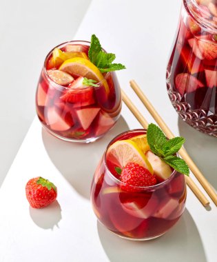 Beyaz restoran masasında kırmızı sangria sürahi ve bardaklar