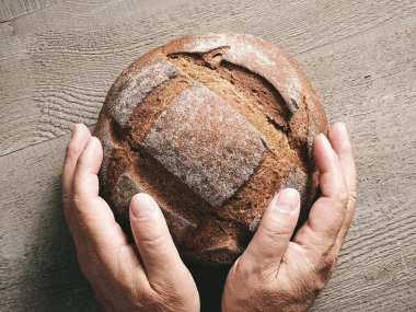 İnsan ellerinde taze pişmiş zanaatkar ekmeği.