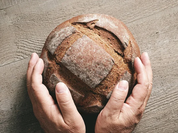 新鲜烘焙的工匠面包在人的手中 顶视图 — 图库照片