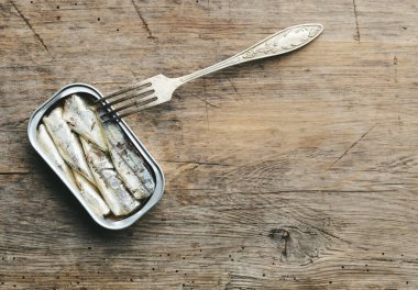 Sardalya konservesi ve çatal eski ahşap mutfak masasında.