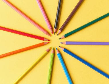 Sarı kağıt zemin üzerinde ahşap renkli kalemler, üst görünüm