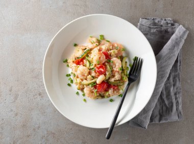 Gri restoran masasında kabak ve karidesli risotto tabağı.