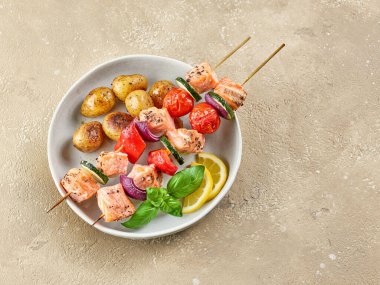 Somon ve sebze şişleri ve restoranın masasında kızarmış patatesler.