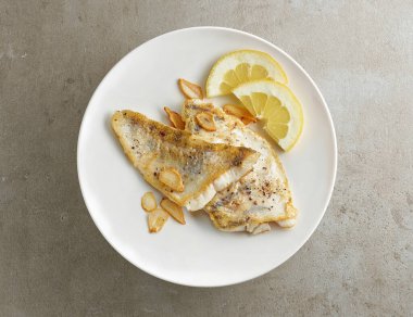 Gri masa arkasında sarımsaklı ve limonlu zander fileto tabağı.